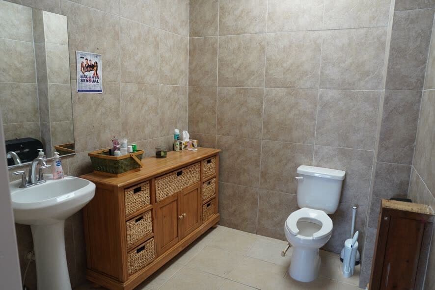 Tiled restroom with a pedestal sink, mirror, and vanity cabinet